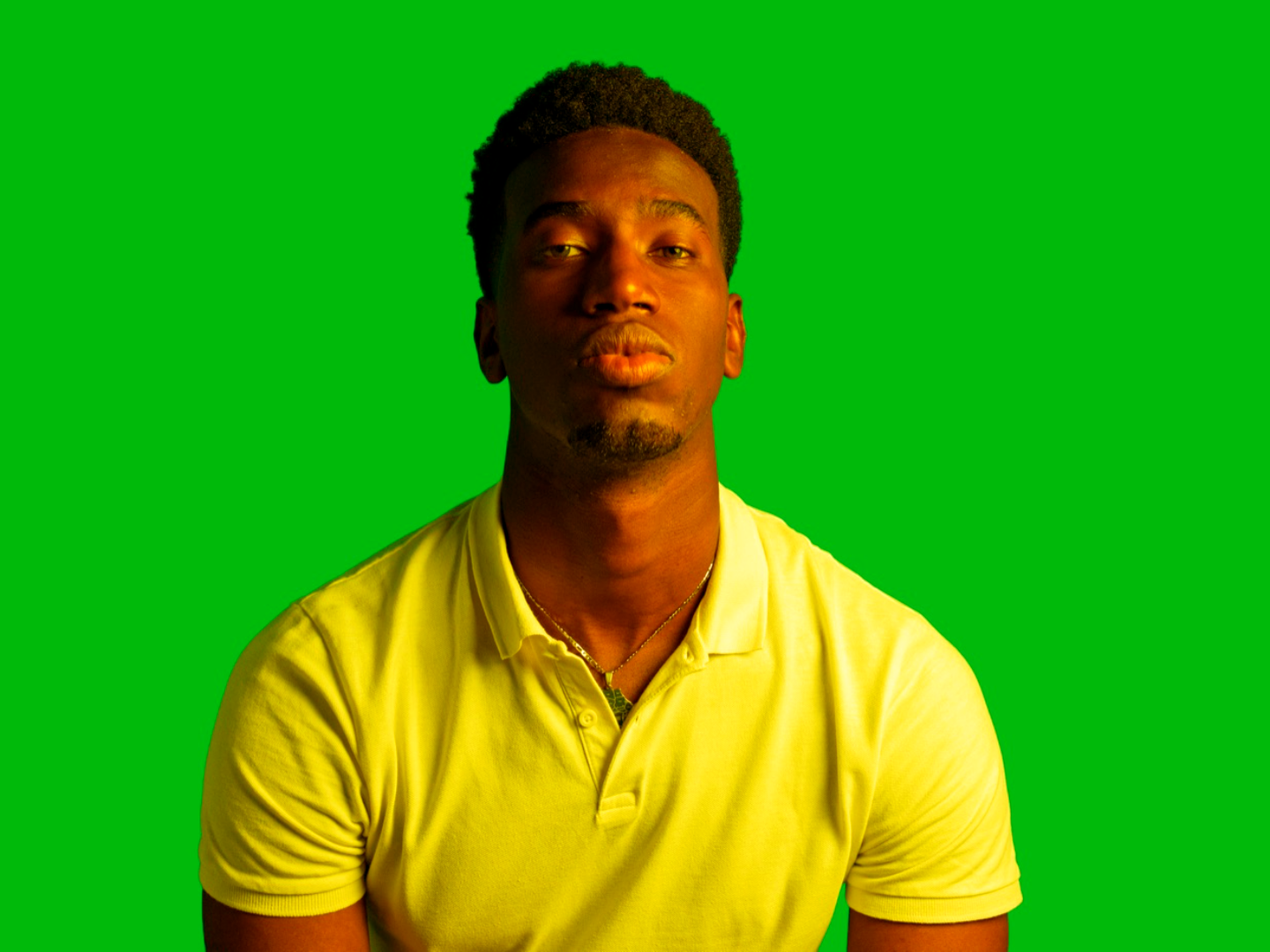 A person in front of a green-screen backdrop with a warm color grade