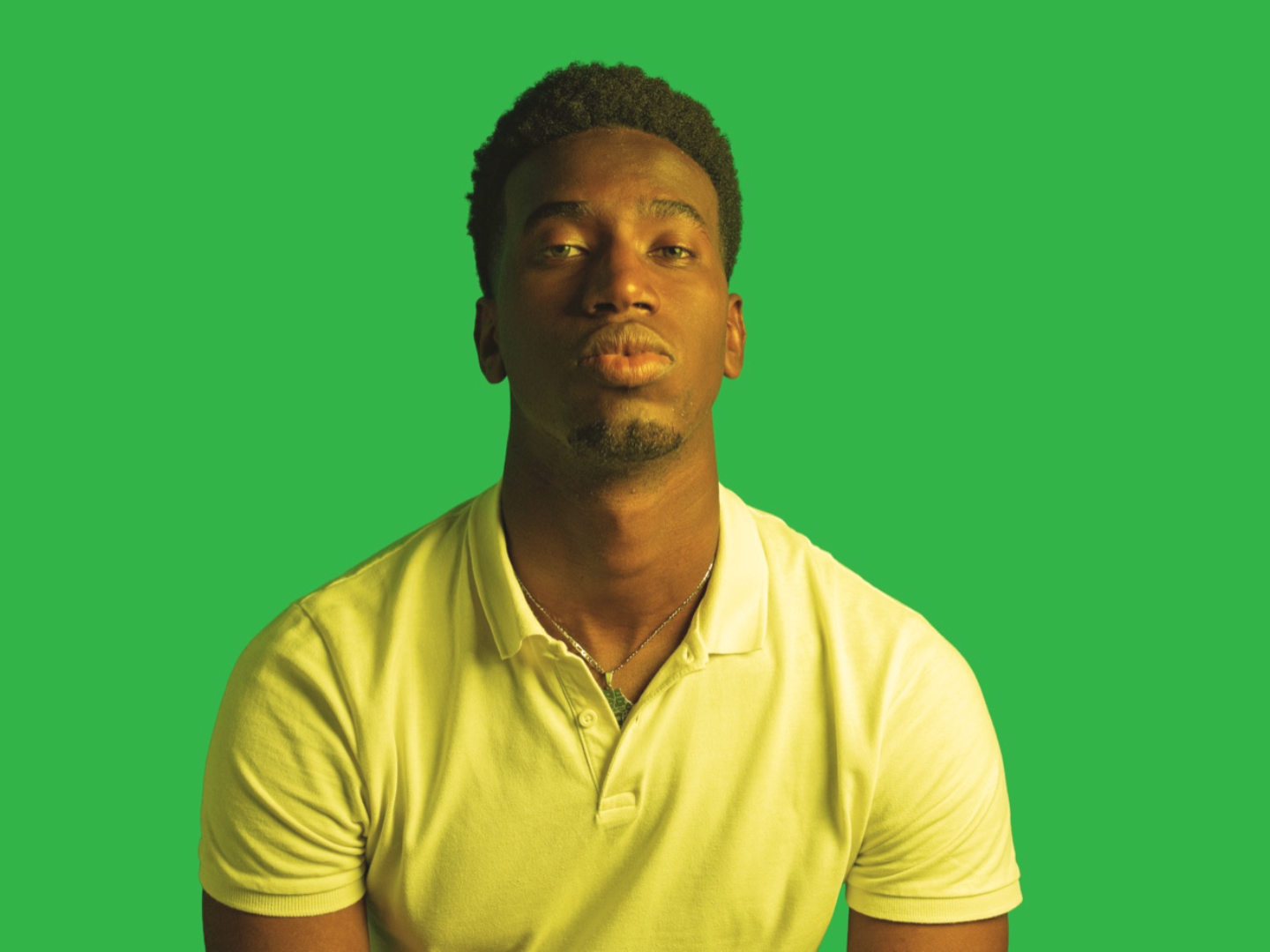 A person in front of a green-screen backdrop with a faded color grade